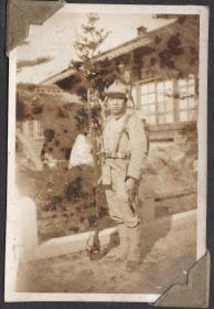 民国时期 手持长刺刀步枪的侵华日军士兵 站在老民房院子中 背后有松树 刺刀和人一样高 老照片 勿忘历史，中华自强
