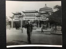 1974年重庆市人民礼堂前一名军人留影及礼堂大门周边行人等景象，可见大门门柱上“伟大的中国共产党万岁”和“中华人民共和国万岁”标语等，15x12cm