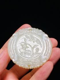 清中期 和田玉籽料白玉 喜得连科 玉珮 玉牌 直径5.7厚0.6厘米 重41.2克 和田白玉籽料，致密温润，洁白无瑕，扁平圆形，正面以卷草纹开光，下承莲花，上饰卷草纹，上下均有穿孔，以便佩戴。开光内浅浮雕夏日荷塘，荷叶田田，莲花摇曳，一只喜鹊展翅，尾羽上翘，正欲飞过荷花枝头。背面阳刻“喜得连科”四字篆书款，布局工整平稳，端庄精致。莲蓬谐音“连科”，莲花、莲叶取连绵不断之意，以白鹭谐