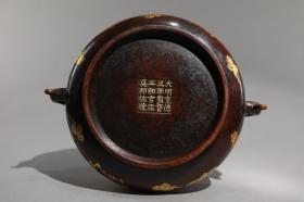 明 精铸铜胎鎏金蝙蝠衔钱纹龙首耳炉 【规格】高8.8cm 口径18.8cm 腹径21cm 耳距24.6cm 重2.7公斤 【款识】大明宣德三年监督工部官臣吴邦佐造 【详述】 铜胎，簋式形制，侈口，微束颈，垂腹，平底，圈足。肩腹两侧各设一龙首耳，兽吞式，线条灵动，威武凌厉。器腹通景浅线阴刻蝙蝠衔钱纹，寓意“福在眼前”。整器形制规整，铸造精良，工艺考究，整饬精确，蜡茶色皮，润泽古意，鎏金装饰