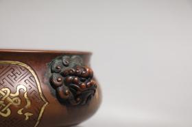 明 精铸铜胎鎏金八宝纹狮首耳炉 【规格】高8cm 口径17.2cm 腹径18.8cm 耳距21.6cm 重2.6公斤 【款识】宣德年制 【详述】 炉身直口，鼓弧腹下收，圈足外撇。颈部两侧对称置双狮耳，狮首涡旋粗眉，双目圆睁，蒜鼻，阔嘴，涡旋长发。腹部卍字纹锦地，阴刻八宝纹纹饰，纹饰细密，层次丰富，寓意非凡。整器形制规整，敦厚之中不失灵巧精致，局部鎏金装饰，雍容典雅，包浆沉稳，色泽典雅