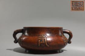 明 精铸铜胎六字真言纹如意耳炉 【规格】高8cm 口径12.4cm 腹径15.4cm 耳距18.2cm 重2.4公斤 【款识】大明宣德年制 【详述】 此炉口沿外撇，束颈，鼓腹，圈足。器壁两侧置对称如意耳，起于颈，而收于腹。“六字真言”阳文周身环置，笔道深俊，细节清晰。六字真言“唵嘛呢叭咪吽”是