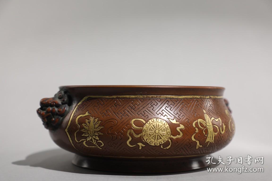 明 精铸铜胎鎏金八宝纹狮首耳炉 【规格】高8cm 口径17.2cm 腹径18.8cm 耳距21.6cm 重2.6公斤 【款识】宣德年制 【详述】 炉身直口，鼓弧腹下收，圈足外撇。颈部两侧对称置双狮耳，狮首涡旋粗眉，双目圆睁，蒜鼻，阔嘴，涡旋长发。腹部卍字纹锦地，阴刻八宝纹纹饰，纹饰细密，层次丰富，寓意非凡。整器形制规整，敦厚之中不失灵巧精致，局部鎏金装饰，雍容典雅，包浆沉稳，色泽典雅