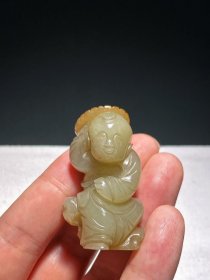 明 和田玉籽料 白玉留皮受沁 持莲童子 把件 挂件 长3宽2.4高5厘米 重42.3克 古代玉雕中，持莲童子是一个长盛不衰的经典题材。这件白玉持莲童子，雕工朴拙，局部留有皮色。童子呈站立状，手持一折枝莲叶绕至头部，整体保留了持连童子题材的常规造型。莲叶边翻折，内雕阴线作脉。双足前后弯曲作半蹲状。童子持莲，寓“连生贵子之意”。