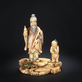 清 寿山石加彩白芙蓉石 道骨仙风 人物立像摆件 长：15 宽：9.5 高：18厘米 此仙人仙童立像由寿山石雕刻而成，呈站立状，立于岩石之上。高鼻深目，面目丰颐，眉须突出，长髯飘逸，慈眉善目，和蔼可亲，充满智慧感，右手托捧葫芦，左手握持拂尘。身着宽袖束腰长袍，衣纹清晰，形态端庄。左边童子腰被葫芦。立像雕塑精湛自然，人物形体线条流畅顺滑，神情、须发雕琢细腻生动。