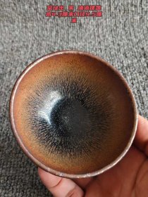 3_窑址出 宋油滴建盏，古韵悠悠。高4.3厘米，口径9.5厘米 。其铁胎质感古朴，釉面独树一帜。黑色油滴斑点散布，似夜空中闪烁的繁星，在棕褐底色映衬下，更显深邃神秘。作为宋代点茶的经典器具，它不仅承载着古人的风雅情趣，更见证了制瓷工艺的辉煌，是历史与艺术交融的珍贵瑰宝。1_AehslN