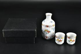 （PA0503）《日本陶瓷酒器》原盒一套 包括酒壶一个 酒杯两个 金边 底部有款 日本传统工艺陶瓷器 外壁花朵图案 设计精美 酒壶口直径：3.4cm 最宽直径：7.3cm 高：13.7cm 酒杯直径：5cm高：5cm 日本陶瓷器的发展自应永年到昭和共经历了500多年的历史，烧瓷行业在不断地发展，技术也在不断地进步，有的已经达到了很高的水平