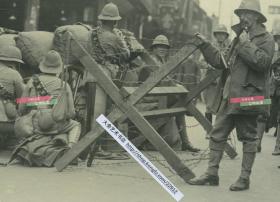 1932年淞沪抗战期间，驻守在上海公共租界的英国士兵驻守在路障之后，守卫在租界入口老照片，附近可见“源记号”商铺以及当铺标志牌等。15.1X10.1厘米，泛银