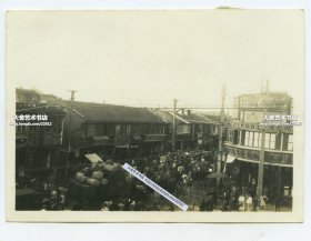 1937年淞沪事变八一三抗战时期，上海华界和法租界的分界处，市民拉着行李进入法租界躲避战乱。可见：裕记同*祥绸缎毛织物商店，泰西绸缎洋货等商铺。8.6X6.1厘米，泛银。