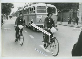 1976年北京的街景老照片，拍摄时正值毛主席去世，路人都左臂带有黑箍，胸前和自行车前都挂有白花，背景是从北京站到和平里的104路无轨电车。29.5X19.8厘米。