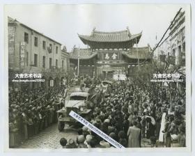 1945年中印公路首次开通后，云南昆明群众在金马牌坊下热烈欢迎首批抵达的运输卡车，可见路旁的国光艺术人像照相馆，建筑上挂着国旗，人们脸上由衷地笑容颜开。22.8X18厘米