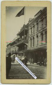 清代旧金山唐人街同仁堂中药店老照片，可见酒楼，楼顶飘扬的大幅的大清龙旗，大约1890年代，铂金斯照相馆拍摄。照片尺寸为18.8X10.8厘米