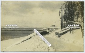 1931年2月冬季雪后的山东威海卫海军公所前面的道路，画面右侧台阶附近是信号站小屋，左侧是铁码头。12.8X7.8厘米，泛银