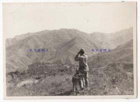 1939~1943年抗日战争期间，北京的门头沟区(当时属河北宛平县)、昌平区、海淀区附近，1个日本士兵带着1条狗，站在山坡上拿望远镜侦察。