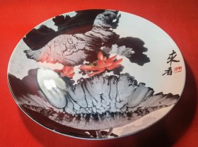 【来者：著名画家、“趣墨画法”创始人来者（原名刘庆书，1952年生于中国吉林省，后旅居巴西）手绘烧制釉下彩趣墨荷花画盘】圆形盘，釉下趣墨彩绘大幅荷花画。盘口直径30.7厘米，底足径19.0厘米，高3.1厘米，壁厚0.3厘米，重1065克。盘面手绘趣墨彩荷花画面。题名款“来者 来者（红色篆印） ”。 该幅趣墨作品为国家领导人作为国礼赠送给巴西总统卡多佐。