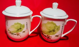 【百财聚来图大型陶瓷茶杯一对】一对共两个，大型茶杯，带原盖，有柄，白釉。名家手绘百财聚来图。中国唐山烧制。整杯通高（含盖）19.0厘米，通长（含柄）15.5厘米，口直径11.5厘米，底足直径6.8厘米，厚度0.3厘米，质量570.0克。杯盖、柄金线饰边。杯体手绘百财聚来图，并题名：“东西南北常进宝 五湖四海广招财”。底款：“中国唐山”。品相好，全新，带原盖，完整无缺，完好无损。