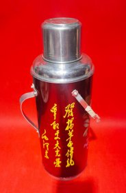 【发扬革命传统 争取更大胜利：上世纪六、七十年代毛主席语录题词红色金属壳老暖水瓶】直径13cm，高17cm，质量810克。北京“鹿牌”，上世纪六、七十年代国营北京保温瓶厂制造。传统水银内保温胆，彩色金属外壳，软木塞，铝质手柄和提手。彩色金属外壳印有毛主席"发扬革命传统 争取更大胜利 毛泽东"金色题词手迹，并绘制彩色花卉画面。全新库存，尚未使用。