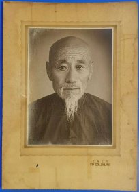 【上海迁京 中国照相：中华老字号中国照相馆1956年从上海迁到北京王府井一位老人大幅肖像照片】原版银盐纸基，黑白布纹泛银老照片。照片净尺寸（长×宽）19.8厘米×14.6厘米。照片镶有中国照相馆原衬板，衬板尺寸（长×宽）31.5厘米×22.8厘米。衬板写有文字“上海迁京 中国照相”。