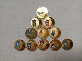《历届奥林匹克运动会吉祥物纪念章/纪念徽章-同一个世界·同一个梦想）》2008年（铜制镀金圆形彩色吉祥物纪念章，Games of the Olympiad、ONE WORLD ONE DREAM，含：德国猎犬--Waldi/瓦尔迪、棕熊“米查”/Misha、小老虎”虎多里"/Hodori、小狗Cobi、Athena/雅典娜和Phevos/费沃斯，福娃贝贝、晶晶、欢欢、迎迎、妮妮）一套存11枚合售