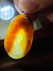 包邮 老料【新疆且末糖青玉老料 糖包肉 小鱼戏莲 椭圆牌】长3.7宽2.35厚0.55重10g，在手近十五年。玉质一眼老货，透光打灯可见下三面糖包肉，只在底部一小块可见肉色。包浆老，手感舒适。雕工一般，但比较写意。加了串绳，性价比高。关键是很润。