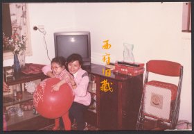八十九十年代，拿着喜字气球的小姑娘，老式电视机，桌上摆放着各种月饼盒子