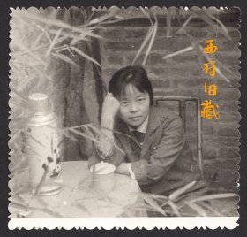 七八十年代，竹影掩映下，在一个摆放着大熊猫暖水瓶的桌子旁的女士人像老照片
