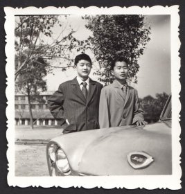 七八十年代，在上海牌汽车前，两个西装革履的青年学生的合影