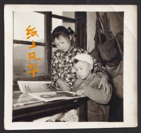 1977年春节，在窗前书桌上，一起认真阅读华主席画报的小姐弟，可见影像内容和时代主题息息相关