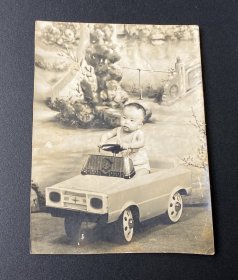 老照片：幼儿开道具小汽车照片（有布景）