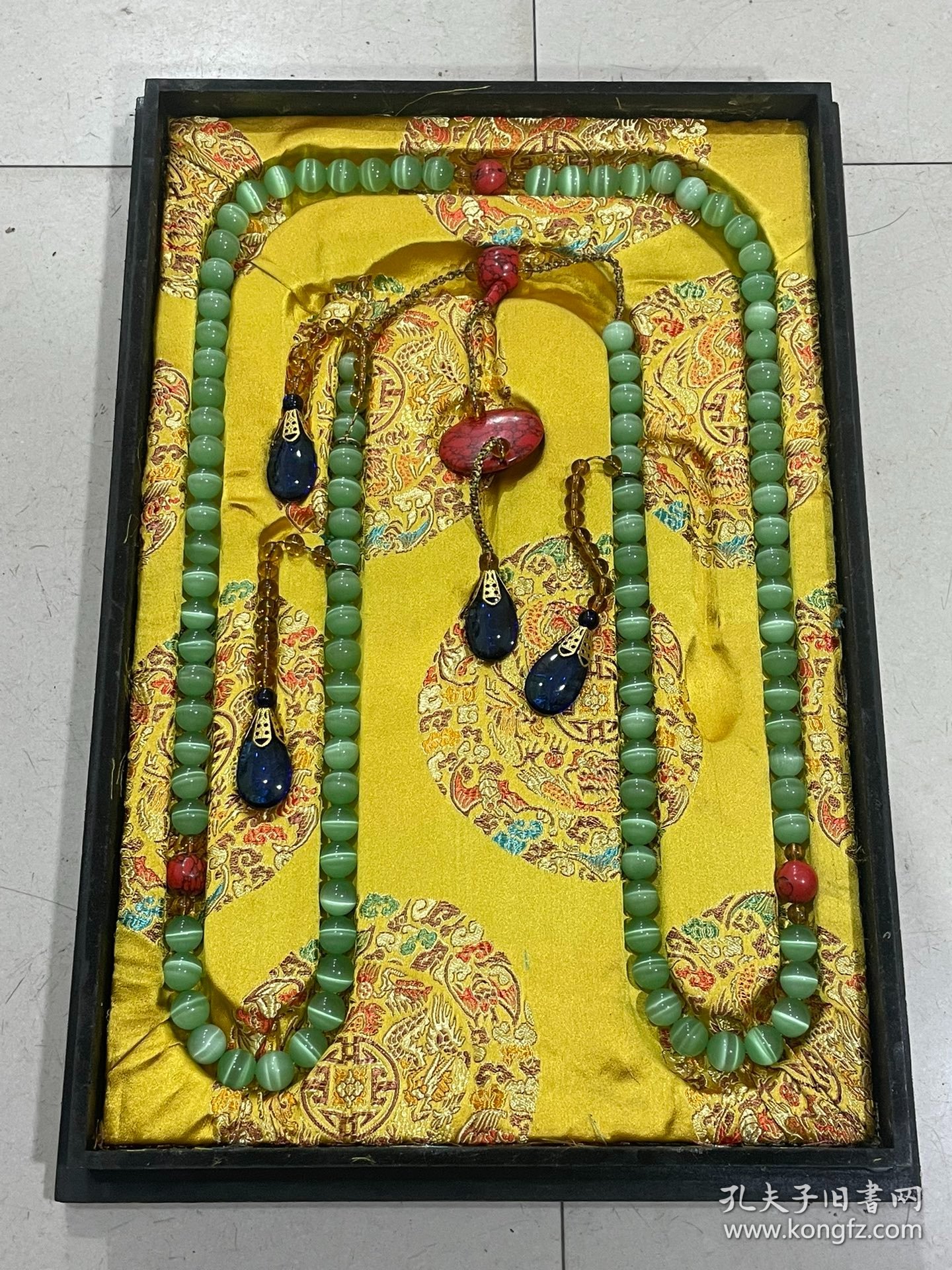 宫廷御用龙纹漆器盒内放猫眼石朝珠 清代朝服上佩带的珠串。朝珠是清朝礼服的一种佩挂物，挂在颈项垂於胸前。朝珠共108颗，每27颗间穿入一粒大珠，大珠共四颗，称分珠，根据官品大小和地位高低﹐用珠和绦色都有区别。 盒子尺寸:长45.5cm，宽30.7cm，高5.5cm