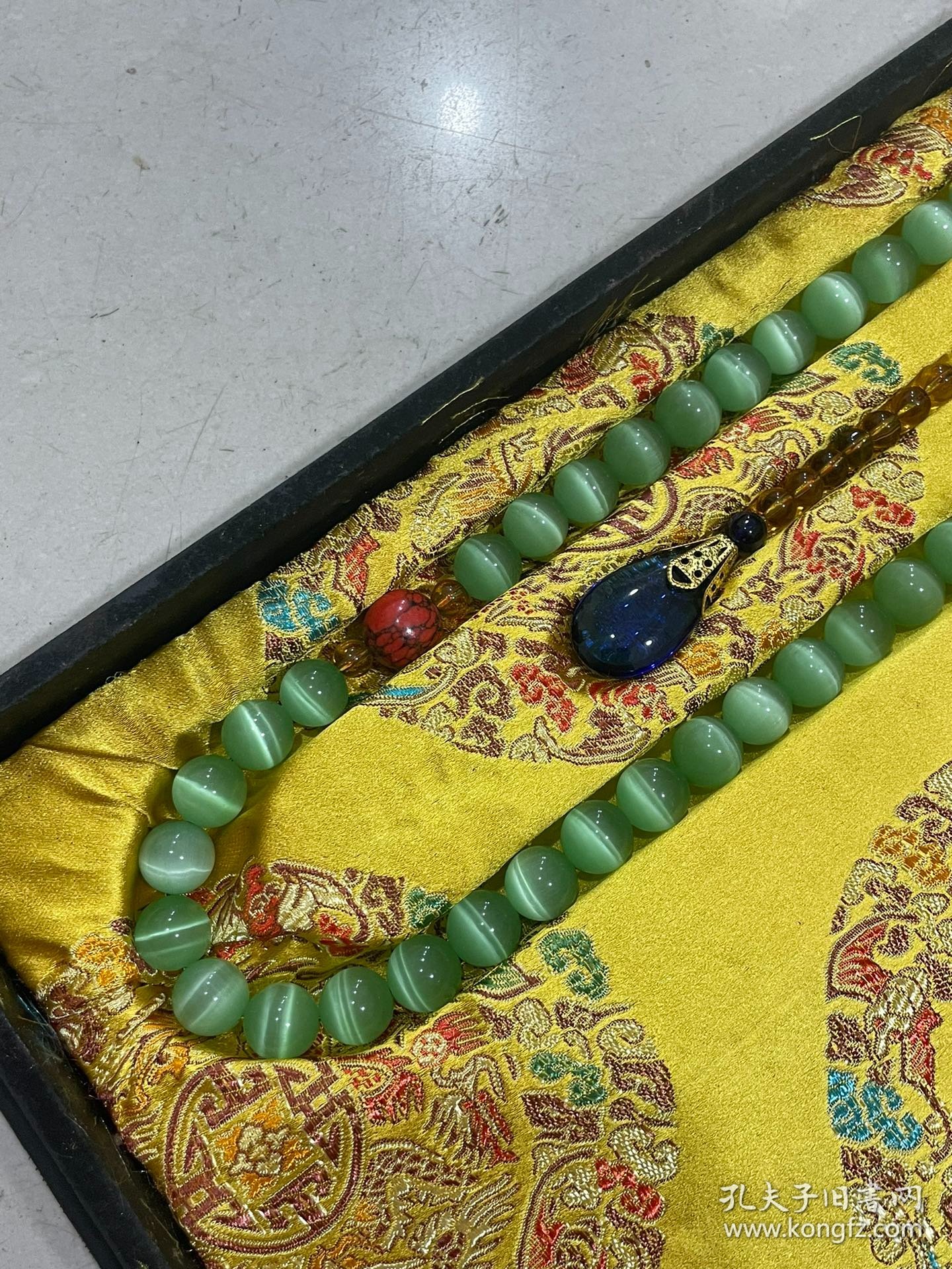 宫廷御用龙纹漆器盒内放猫眼石朝珠 清代朝服上佩带的珠串。朝珠是清朝礼服的一种佩挂物，挂在颈项垂於胸前。朝珠共108颗，每27颗间穿入一粒大珠，大珠共四颗，称分珠，根据官品大小和地位高低﹐用珠和绦色都有区别。 盒子尺寸:长45.5cm，宽30.7cm，高5.5cm