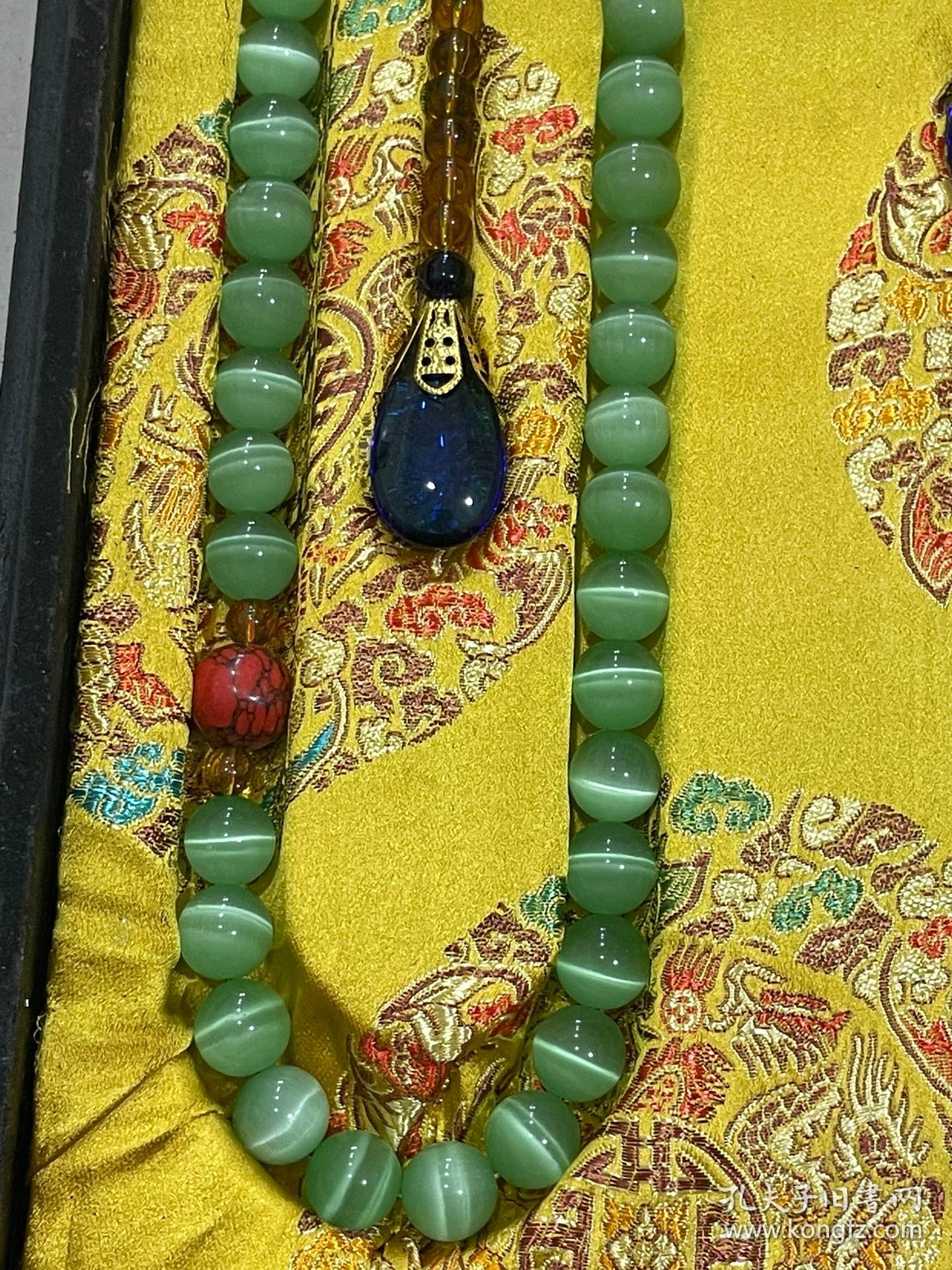 宫廷御用龙纹漆器盒内放猫眼石朝珠 清代朝服上佩带的珠串。朝珠是清朝礼服的一种佩挂物，挂在颈项垂於胸前。朝珠共108颗，每27颗间穿入一粒大珠，大珠共四颗，称分珠，根据官品大小和地位高低﹐用珠和绦色都有区别。 盒子尺寸:长45.5cm，宽30.7cm，高5.5cm