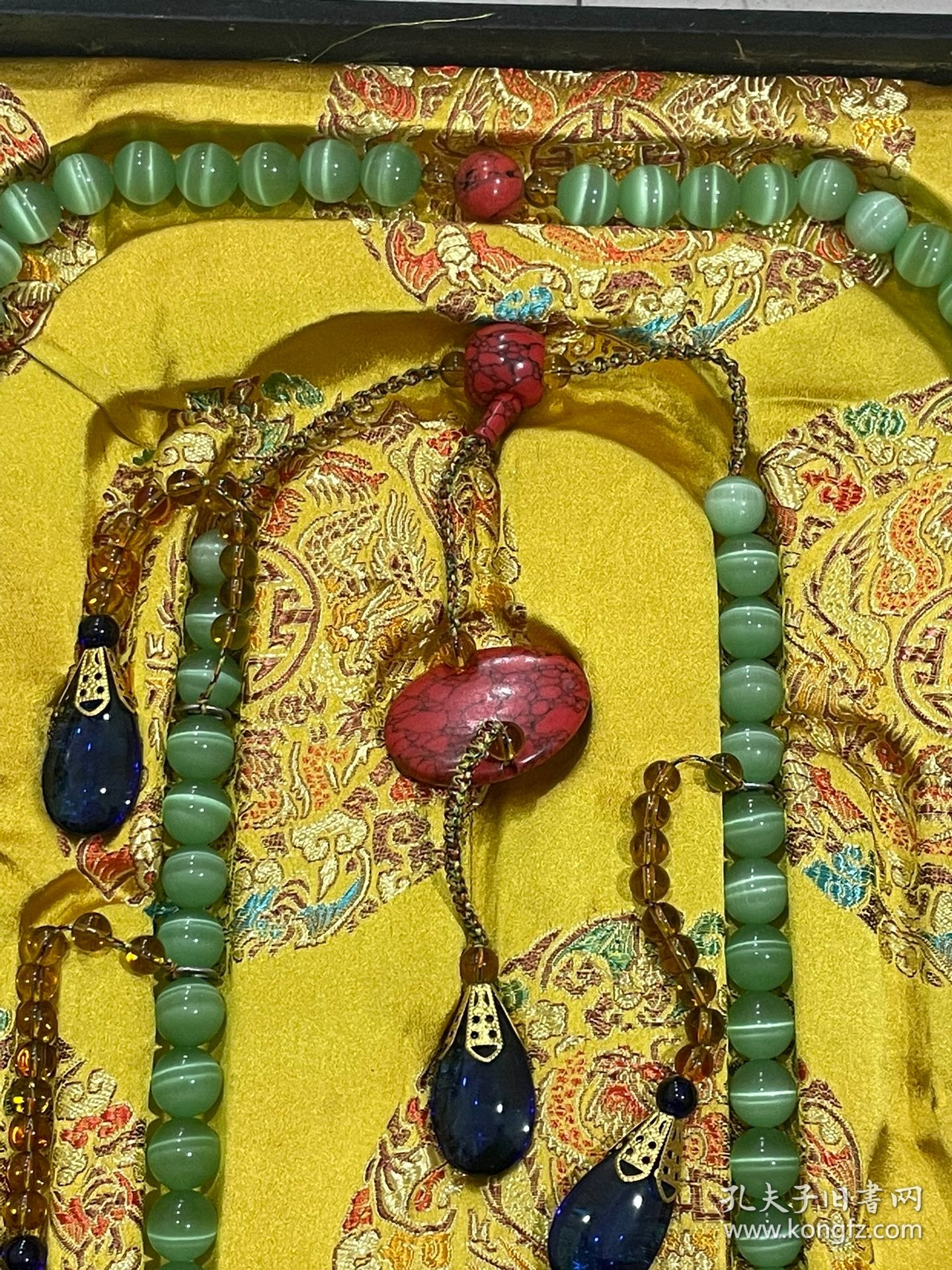 宫廷御用龙纹漆器盒内放猫眼石朝珠 清代朝服上佩带的珠串。朝珠是清朝礼服的一种佩挂物，挂在颈项垂於胸前。朝珠共108颗，每27颗间穿入一粒大珠，大珠共四颗，称分珠，根据官品大小和地位高低﹐用珠和绦色都有区别。 盒子尺寸:长45.5cm，宽30.7cm，高5.5cm