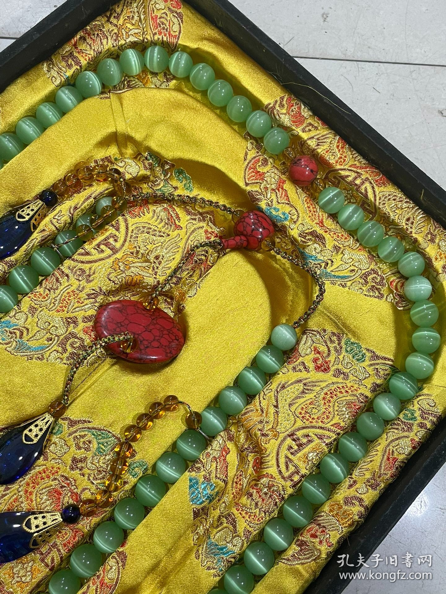 宫廷御用龙纹漆器盒内放猫眼石朝珠 清代朝服上佩带的珠串。朝珠是清朝礼服的一种佩挂物，挂在颈项垂於胸前。朝珠共108颗，每27颗间穿入一粒大珠，大珠共四颗，称分珠，根据官品大小和地位高低﹐用珠和绦色都有区别。 盒子尺寸:长45.5cm，宽30.7cm，高5.5cm