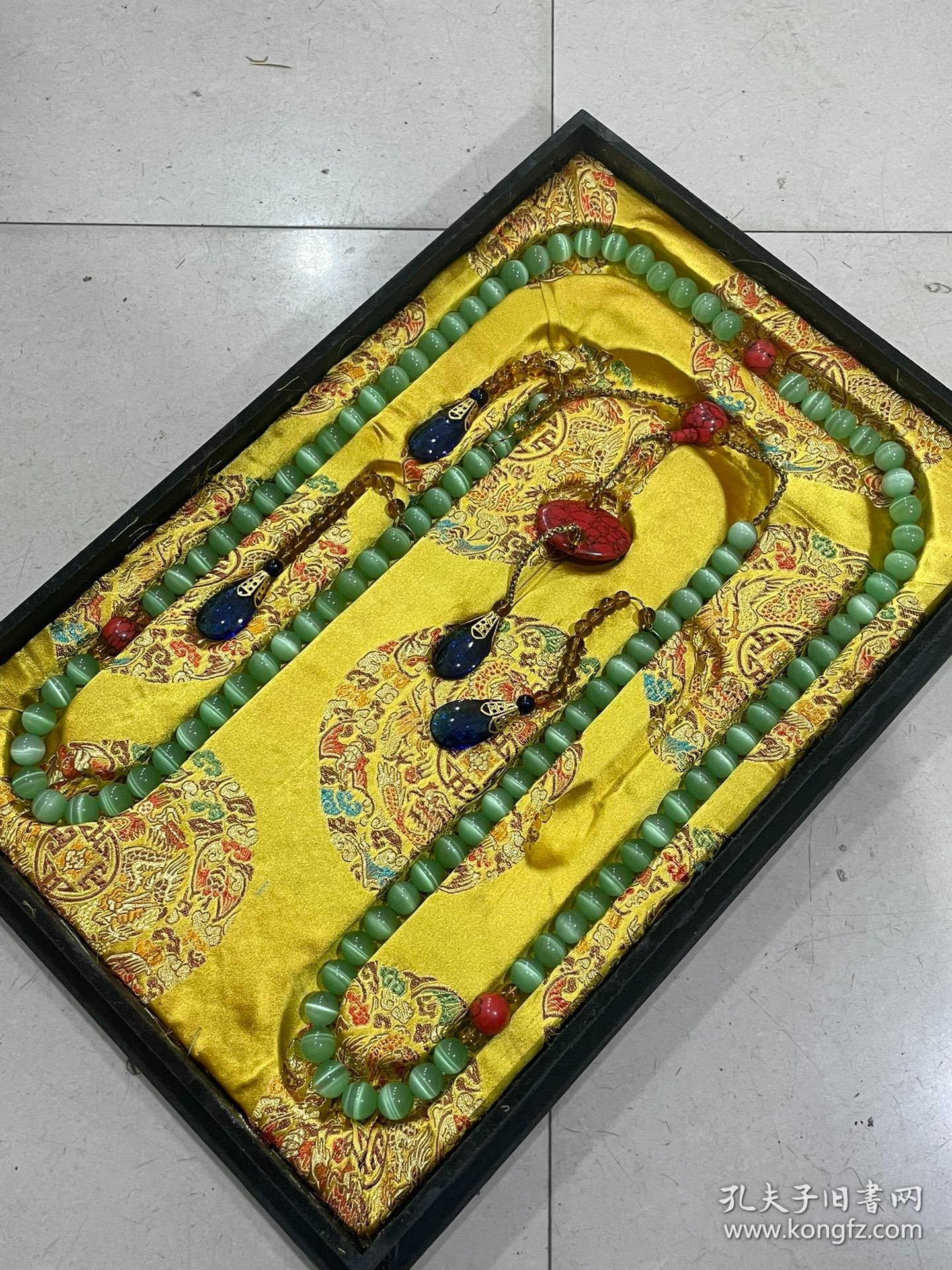 宫廷御用龙纹漆器盒内放猫眼石朝珠 清代朝服上佩带的珠串。朝珠是清朝礼服的一种佩挂物，挂在颈项垂於胸前。朝珠共108颗，每27颗间穿入一粒大珠，大珠共四颗，称分珠，根据官品大小和地位高低﹐用珠和绦色都有区别。 盒子尺寸:长45.5cm，宽30.7cm，高5.5cm