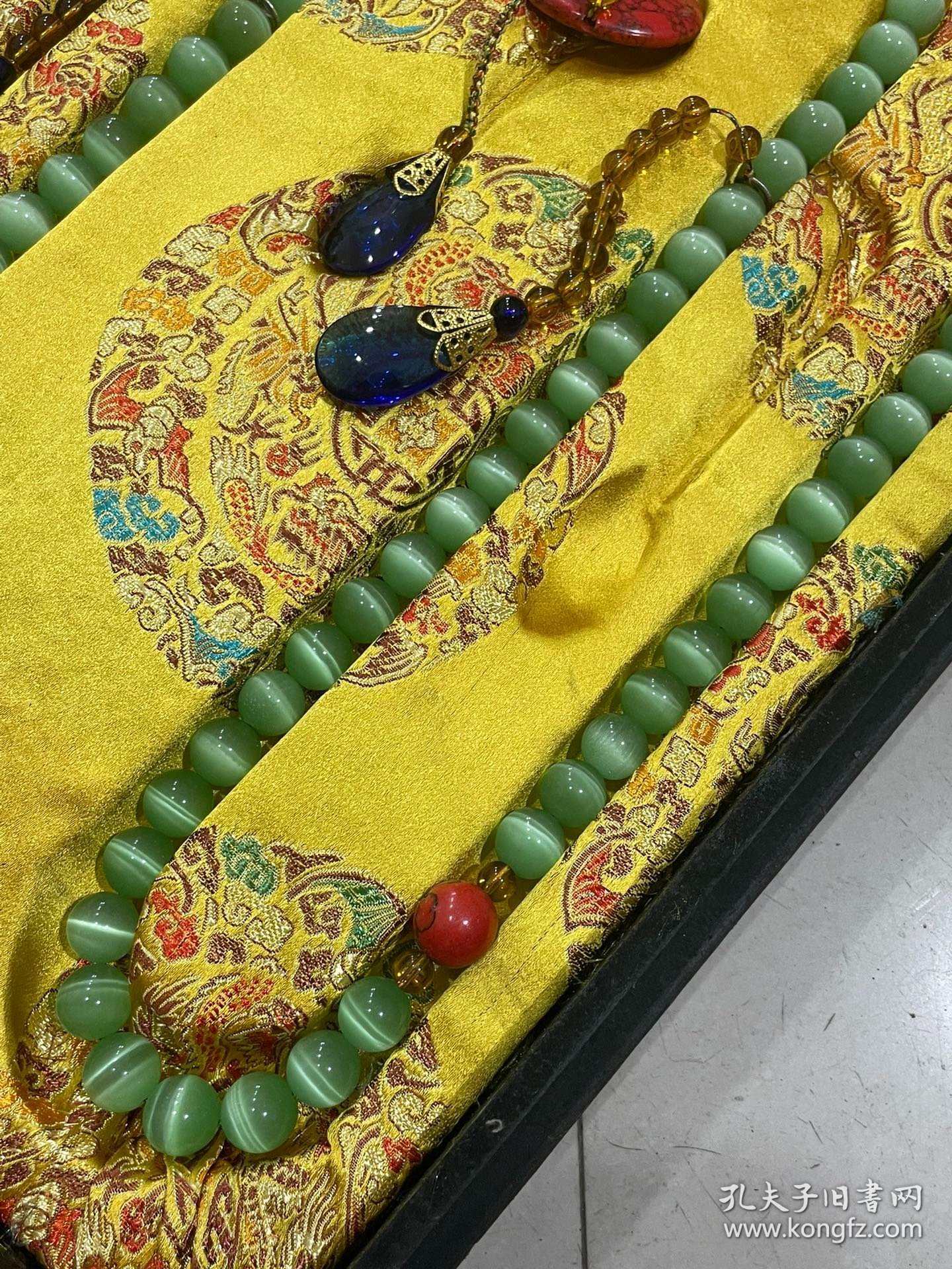 宫廷御用龙纹漆器盒内放猫眼石朝珠 清代朝服上佩带的珠串。朝珠是清朝礼服的一种佩挂物，挂在颈项垂於胸前。朝珠共108颗，每27颗间穿入一粒大珠，大珠共四颗，称分珠，根据官品大小和地位高低﹐用珠和绦色都有区别。 盒子尺寸:长45.5cm，宽30.7cm，高5.5cm