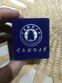【校徽收藏】云南财经大学校徽一枚【配有原装小锦盒】全新没有使用过的，表面贴有保护膜，图片为实拍，品相以图片为准。直径2.5cm【学校老师家里收到的，应该是学校老师或是领导使用的专用校徽，不是学生用的】
