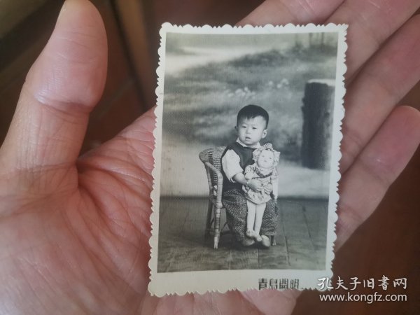 照片：50年代小朋友坐藤编椅手拿娃娃（青岛开明）