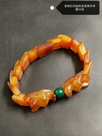老南红玛瑙双龙戏珠手串，重53克。颗颗玛瑙色泽浓郁，橙红流转间尽显古朴韵味。双龙造型栩栩如生，似在灵动嬉戏，搭配翠绿圆珠，更添几分雅致。它从时光深处走来，不仅是精美的饰品，更是承载岁月记忆与传统工艺魅力的珍藏之物。
