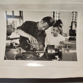 1973年，美丽的西双版纳景德工厂哈尼族老工人李志明，在帮助傣族新工人玉浪掌握车床的操作技术。 尺幅15*11cm