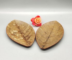 日本天然树叶茶托盘2片，纯手工制作，叶脉纹理清晰自然。红色边框装饰。树叶经过特殊工艺处理，保存完好，可做茶托、杯垫、小碟使用。喜欢的朋友可以入手。长16.5厘米，宽9厘米，厚0.1厘米。