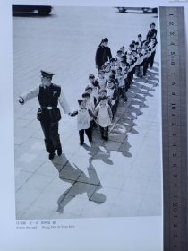 1957年王一波、袁柯复拍摄的《过马路》，正反面印刷画，20多位70多年前的小朋友还健在吗？有你吗？背面画4幅，分别为：苏良质摄：公社晨钟；苏湘摄：渔港归舟；唐允仁摄：我们公社的大肥猪；王长春摄：人民公社的棉花收购站，图画尺寸祥见实物拍照所示。