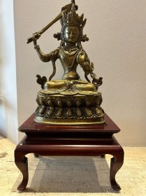 举剑文殊菩萨像，纯铜精制，开脸大方，宽约20厘米，深11厘米，高约33厘米，重达2.6 kg，大摆件，底部内腔未封，结构清晰可见，妥妥的年代老物件。缺陷是在图中我手指处一飘带有断的痕迹，余好，摆设的小木桌是搭配的。需要另购