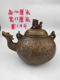 旧藏:【龙凤狮扭提梁铜壶】 尺寸：高14cm壶宽17cm重1.9斤。 这款龙凤铜壶，铜胎，帽形盖，盖顶饰狮子扭盖，壶腹大致呈圆形，壶身阴雕龙凤，神韵十足，矮圈足。壶体以园雕、阴刻组合纹饰，生动形象，寓意深长，整体包浆浓郁，品相一流。收藏佳品！