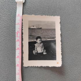 可爱小孩坐海边老照片
