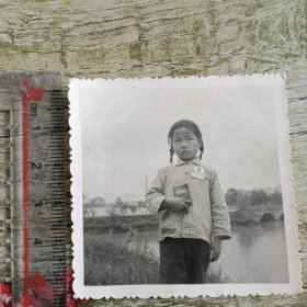 撅着嘴佩戴毛主席像章手拿红宝书的小姑娘黑白照片一张