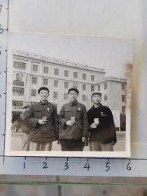 时期干部佩戴毛主席像章手持红宝书在挂有毛主席像的建筑物前合影照片“把无产阶级进行到底!”(韩永福相册)