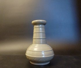 古越窑秘色釉弦纹剔花瓶，釉色青纯，玉质感强。器型稳重，手抓感好。剔花精美，弦纹露筋，边缘深浅有别。5个细芝麻钉，小巧美观。镜下可见结晶明显，火石红微微泛出，缩釉及细黑颗粒可见。内观拉坯工整，旋纹明显。千年真品，世所罕见。