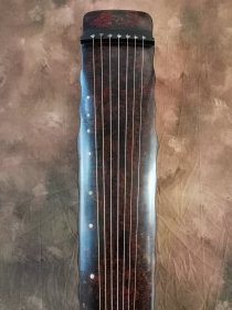 【金徽】落霞式 玉轸足 造型简洁朴素，声音清雅纯正。桐木制，轮廓线条挺拔有力，岳尾以紫檀制。琴面髹犀皮色漆，漆层致密，琴底髹暖栗色漆与深褐色漆。规整雅致，制作精良。金徽星罗井然，木轸如月华，精巧雅致。长方形龙池凤沼，龙池上刻 金徽二字，填有金痕，其音清朗松透，古朴内敛，实为存世古琴的可圈可点之作。