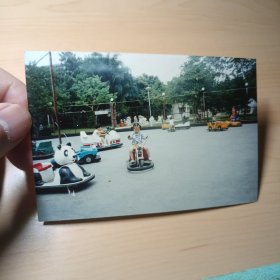 老照片–小女孩在游乐场骑碰碰车留影（左侧有一个熊猫碰碰车）